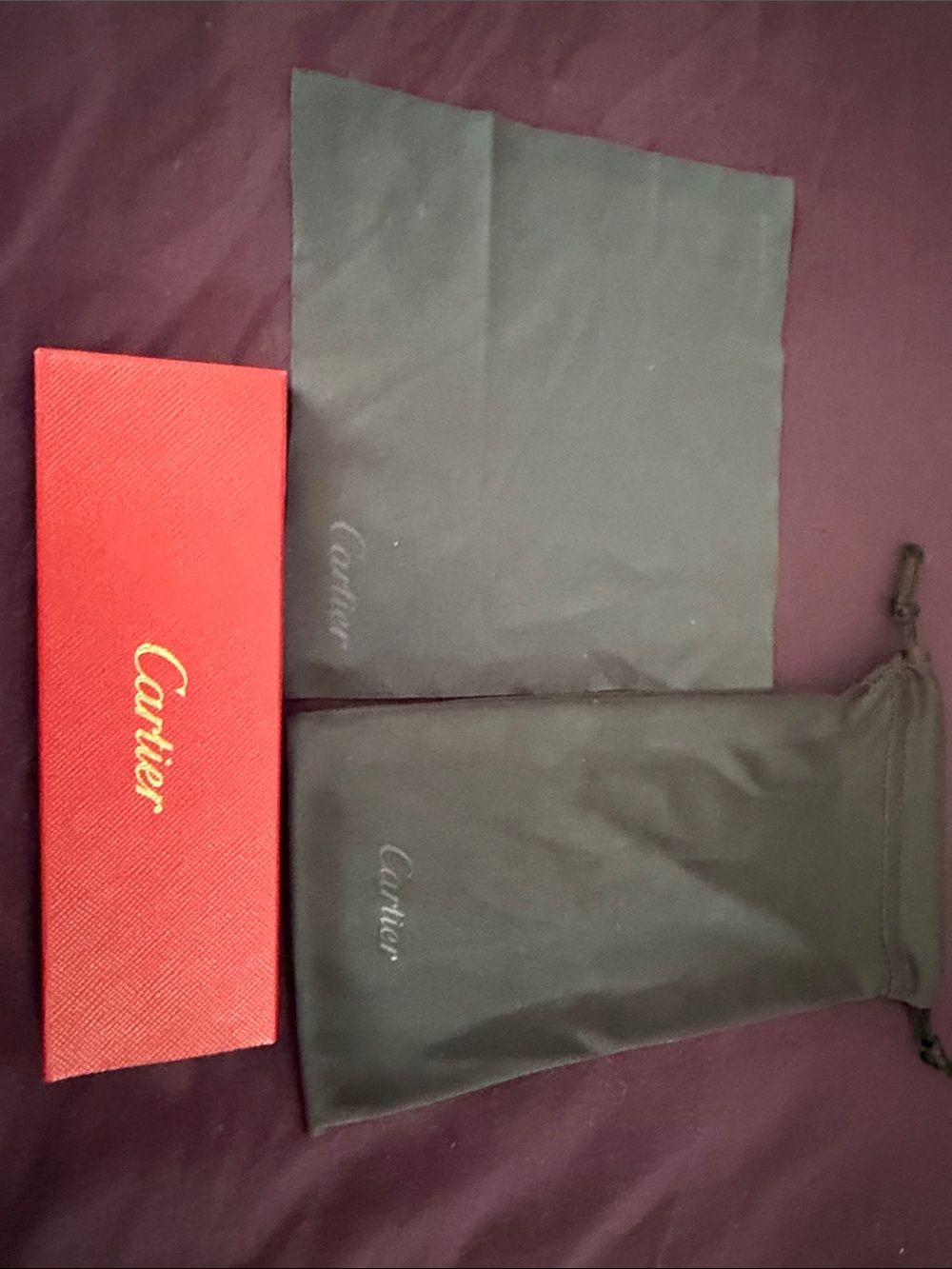 Cartier red box with gold logo and black drawstring pouches